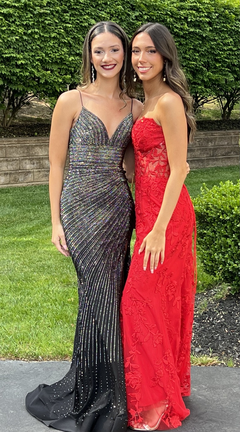 Two girls in prom dresses — sparkly black and red lace gowns